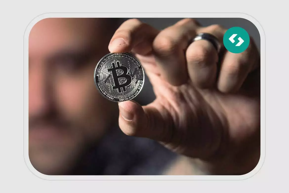 Homem segurando uma moeda com um B de Bitcoin, representando a moeda digital