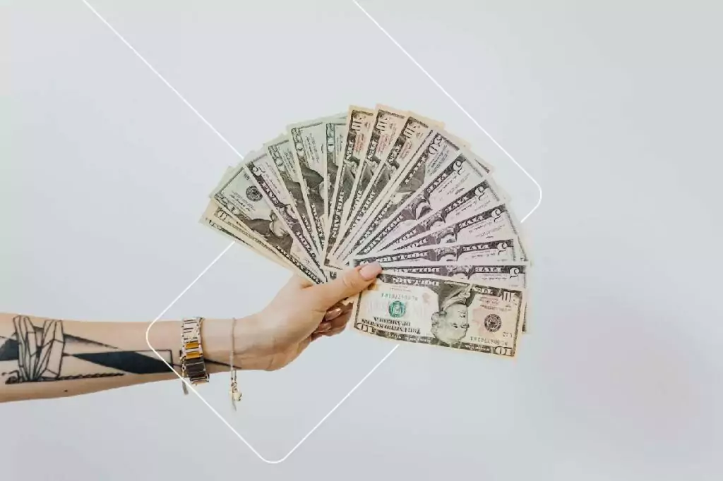Mão de uma pessoa segurando várias notas de dólares